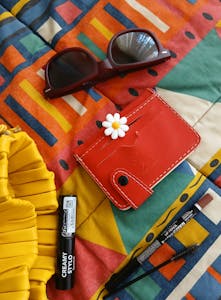 Vibrant accessories including sunglasses and wallet on geometric fabric.